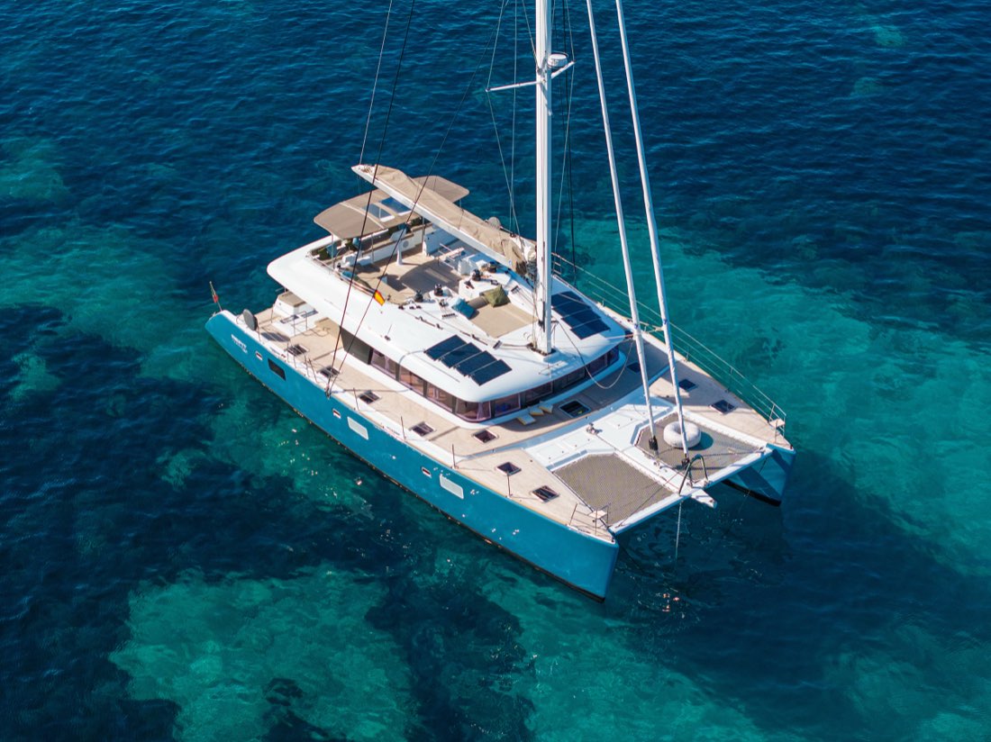 Lagoon 620 NEO vor Anker in türkisem Wasser, Luftaufnahme
